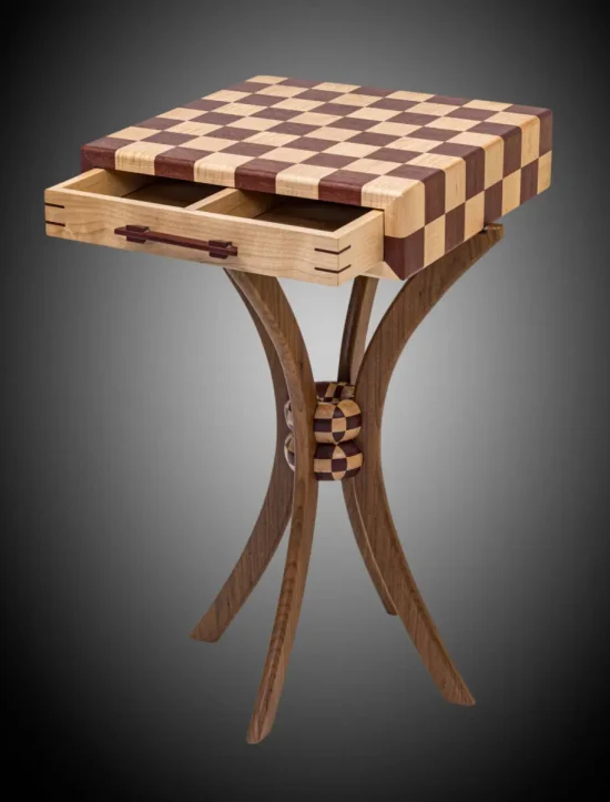 Wooden chessboard table with two open drawers, featuring curved legs and a checkered design on the tabletop.