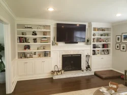Living room with built-in shelves, a fireplace, and a large TV mounted above the mantel.