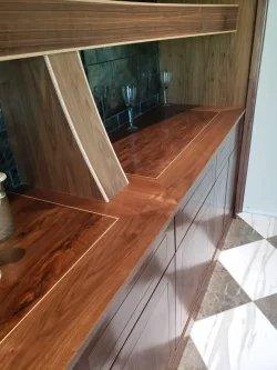 Wooden countertop with angled supports, glassware on a tiled backsplash, and checkered marble flooring.