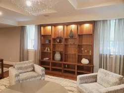 Two armchairs face a large wooden shelving unit with decorative vases and objects, set in a modern living room.