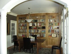 Dining room with a wooden table, four chairs, and built-in bookshelves filled with books and decorative items.