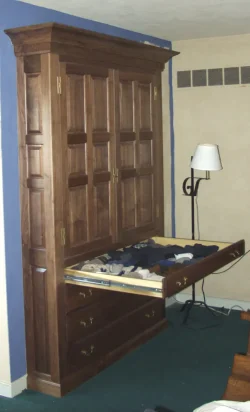 Tall wooden wardrobe with paneled doors and drawers, one drawer open showing neatly organized socks.