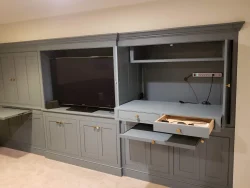 Built-in gray cabinetry with a TV, open shelves, power strip, and two drawers partially pulled out.