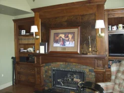 Wood-paneled fireplace with bookshelves, framed art, brass scales, and a TV in a traditional study or living room.
