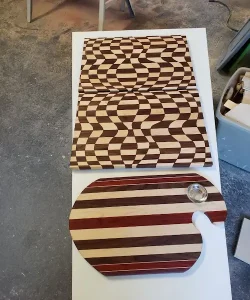 Two wooden boards: one with an optical illusion wavy pattern, the other shaped like an artist's palette with stripes.