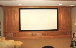 Home theater room with a large blank projector screen set in a wooden frame, beige carpet, and recessed lighting.