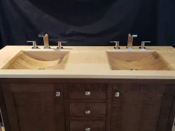 Double bathroom vanity with two square sinks, chrome faucets, and a wooden countertop and cabinet against a dark background.
