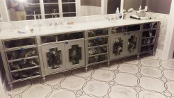 A modern bathroom with a long mirrored vanity, double sinks, marble countertop, and geometric tile floor.