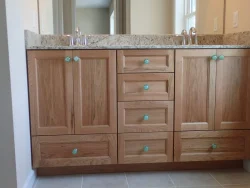 Double bathroom vanity with wood cabinets, granite countertop, dual sinks, and turquoise drawer knobs.