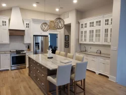 Modern kitchen with a large island, white cabinets, stainless steel appliances, and pendant lights above the island.