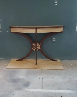 A wooden console table with curved legs and a decorative checkered sphere at the center, placed against a blue wall.
