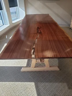 A large wooden table with a natural, uneven split running through the center, placed in a sunlit room.